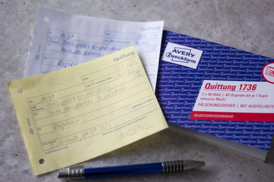 Ein Quittungsblock von Avery Zweckform liegt auf einem Tisch. Man sieht eine handschriftlich ausgefüllte Quittung inklusive Durchschlag. 