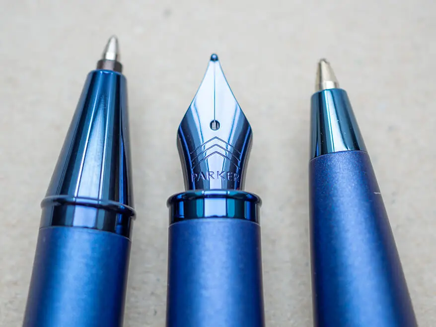 Ein blauer Tintenroller, ein Füllfederhalter und ein Kugelschreiber von Parker liegen auf einem hellgrauen Untergrund. Foto: Johanna Rundel