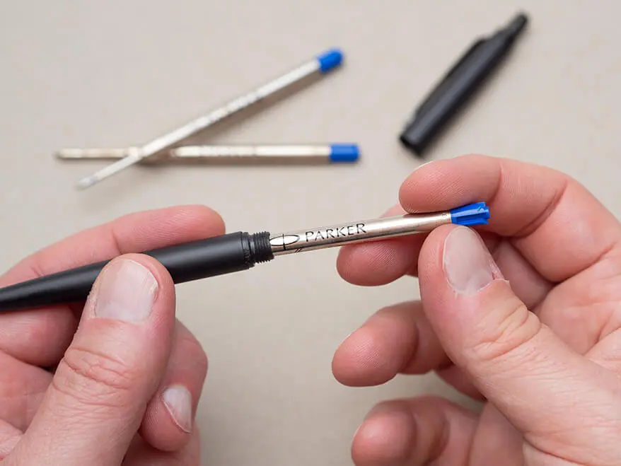 Jemand wechselt die Mine eines schwarzen Kugelschreibers von Parker. Der Hintergrund ist hellgrau. Foto: Johanna Rundel