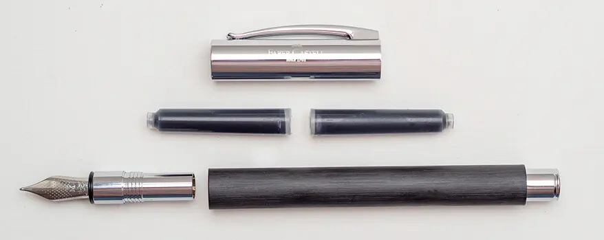 Die Einzelteile eines auseinandergebauten, schwarzen Füllers von Faber-Castell liegen symmetrisch angeordnet auf einem hellen Untergrund. Foto: Johanna Rundel