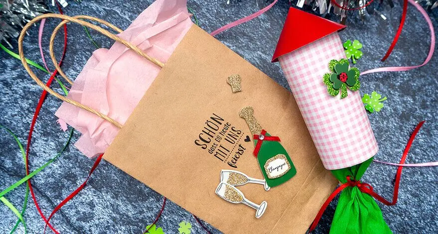 Auf einem dunkelgrauen Untergrund liegen eine gestaltete Papiertüte und eine selbstgebastelte Silvesterrakete aus Bastelmaterialien von HEYDA und KNORR prandell. Foto: Johanna Rundel