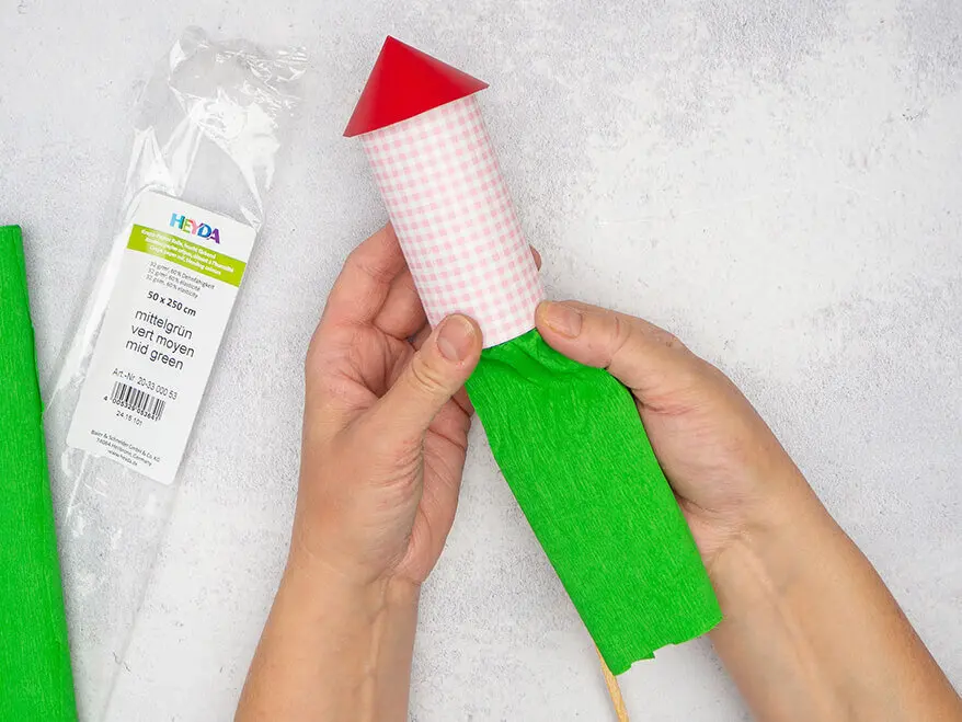 Jemand klebt grünes Krepppapier von HEYDA auf die Innenseite einer selbstgebastelten Silvesterrakete aus Papier. Foto: Johanna Rundel 