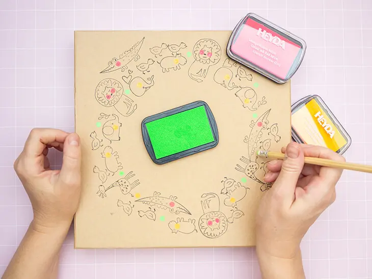 Jemand tupft mit dem Radiergummi-Ende eines Bleistiftes neonpinke Stempelfarbe von HEYDA auf den Deckel einer Pappschachtel von KNORR prandell. Foto: Johanna Rundel