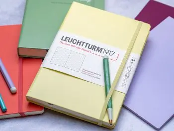 Viele verschiedenfarbige Notizbücher und Journals der Marke LEUCHTTURM1917 liegen auf einem grauen Untergrund verteilt. Foto: Johanna Rundel