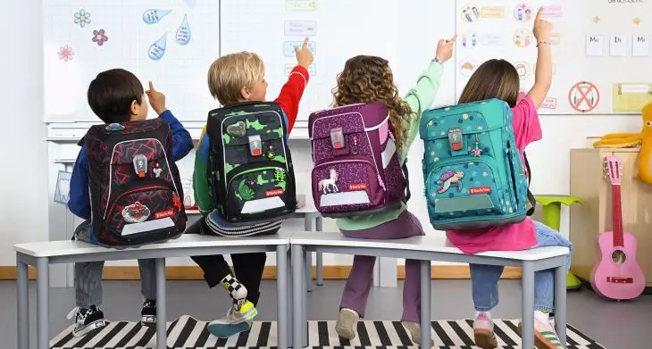 Vier Kinder mit verschiedenen Step by Step Schulranzen in einem Klassenzimmer.