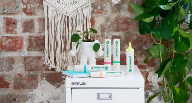 Ecoline Highlighter von edding auf einer Kommode, im Hintergrund Wand mit Makramee und Kletterpflanze