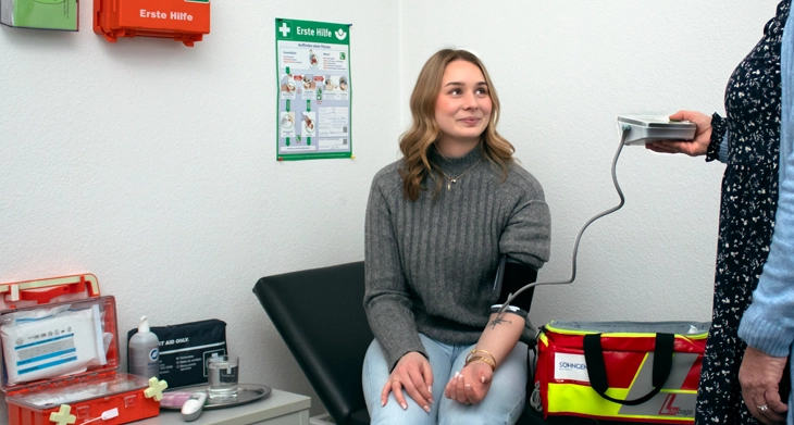 Ersthelferin misst den Blutdruck einer jungen Frau im Erste-Hilfe-Raum.