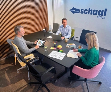 3 Personen sitzen an einem Tisch in einem Meeting