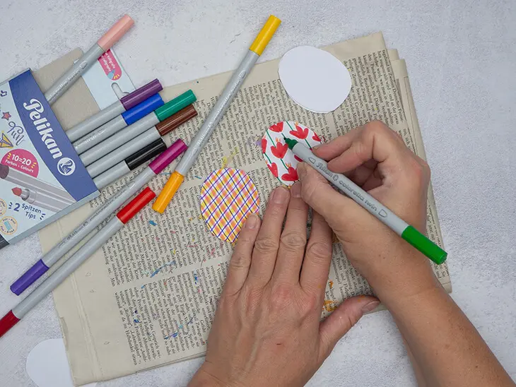 Jemand schneidet mit einer griffix-Schere von Pelikan einen Halbkreis von einem gefalteten Stück lila Papier ab. Foto: Johanna Rundel