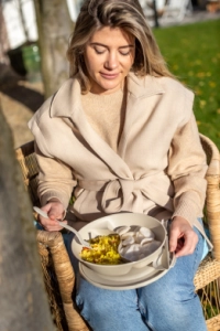 Eine Frau isst ihr Essen im Freien.