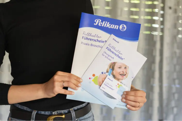 Eine Frau hält die Unterlagen zum Füllhalter-Führerschein von Pelikan in den Händen.