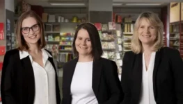 Drei Frauen lächeln in die Kamera.