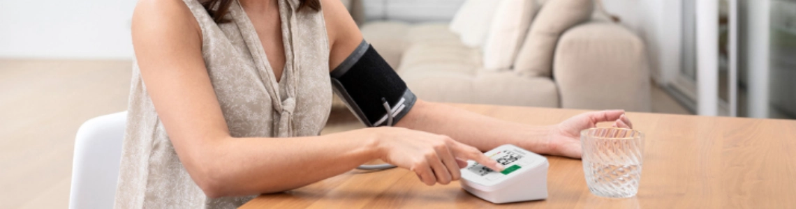 Frau misst Blutdruck mit Oberarm-Blutdruckmessgerät.