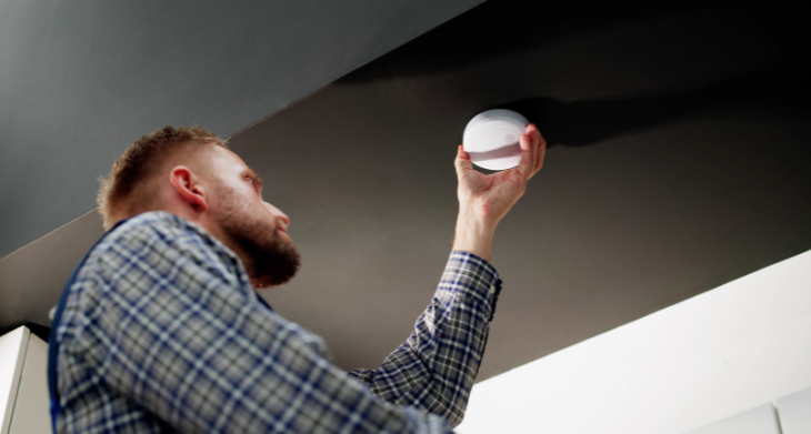 Ein Mann hängt einen Melder auf.