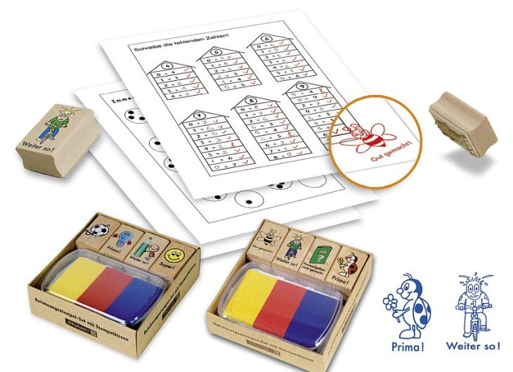 Abbildung von Arbeitsblättern aus der Grundschule, welche mit einem Belohnungsstempel versehen sind. Daneben liegen Sets von Belohnungsstempeln und Abbildung diverser Motive von Belohnungsstempeln.