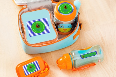 Auf einem Tisch liegen Brotdosen und Trinkflaschen, welche mit Namensetiketten von Avery Zweckform beklebt sind.