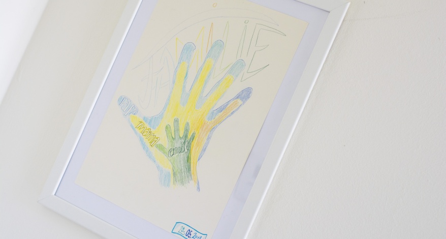 Gerahmte Zeichnung mit bunten Handabdrücken und dem Wort „Familie“