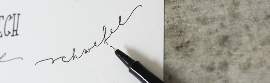 Close-up eines beletterten Papiers neben dem ein geöffneter schwarzer Fineliner liegt.