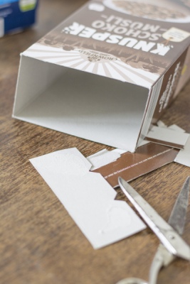 Von einem Müslikarton wurden die Laschen abgeschnitten. Die Schere liegt daneben.