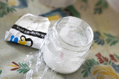 Glas mit weißer Farbe, abgedeckt mit Frischhaltefolie