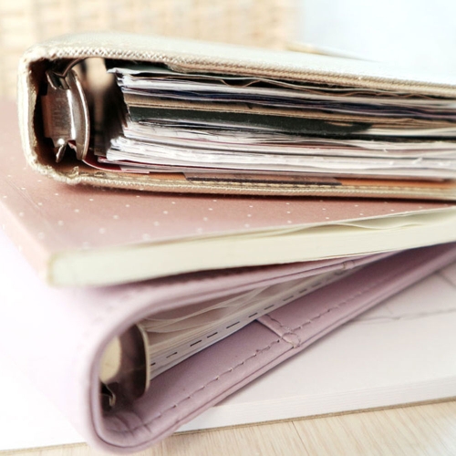 Aufgestapelte Filofax-Ringbücher zeigen seitlich die eingehefteten Seiten.