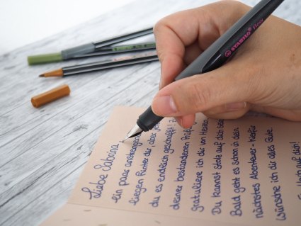 Jemand schreibt mit Füller eine Karte