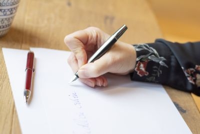 Nahaufnahme von Hand, die mit Füllhalter Pura von Pelikan auf ein Blatt Papier schreibt. Übungen für die Schönschrift.