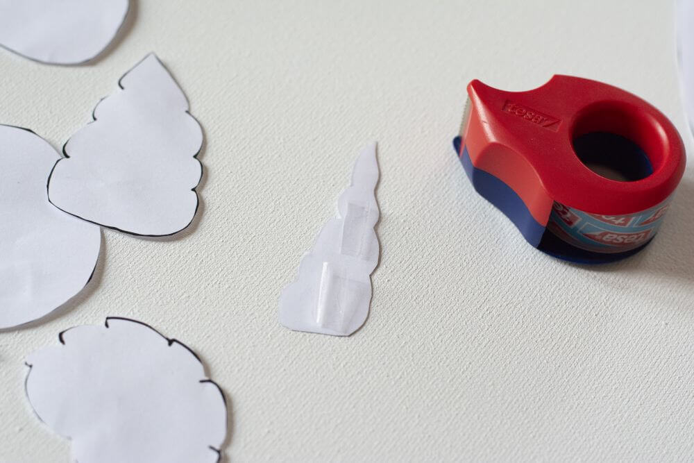 Nahaufnahme einer Schablone einer Seeschnecke aus Papier, die mit Klebestreifen versehen ist.