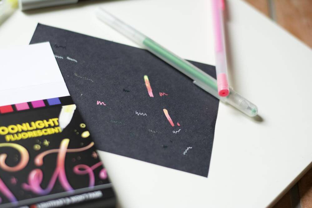 Nahaufnahme eines dunklen Schmierpapiers, auf dem die Eigenschaften der Gelstifte "Gelly Rolls" von Sakura getestet wurden.