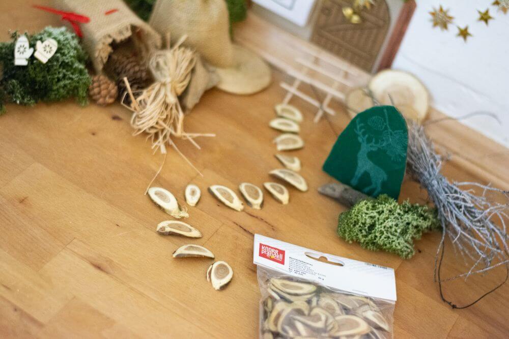 Detailaufnahme einer selbstgemachten Wichteltür: Holzscheiben als Basteldeko von Knorr Prandell liegen als Fußweg für den Weihnachtswichtel auf dem Parkettboden.