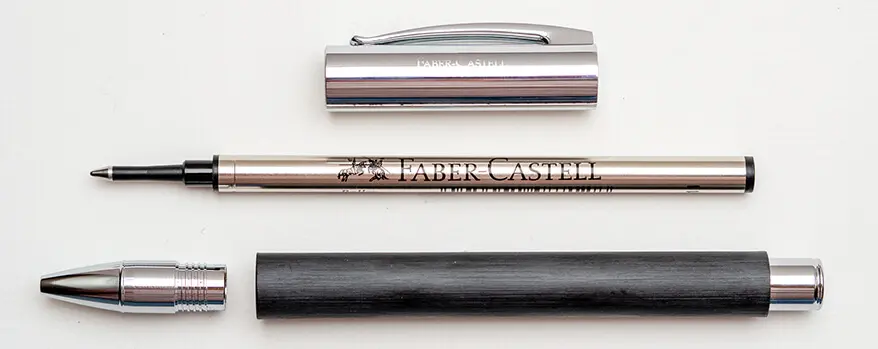 Die Einzelteile eines auseinandergebauten, schwarzen Tintenrollers von Faber-Castell liegen symmetrisch angeordnet auf einem hellen Untergrund. Foto: Johanna Rundel
