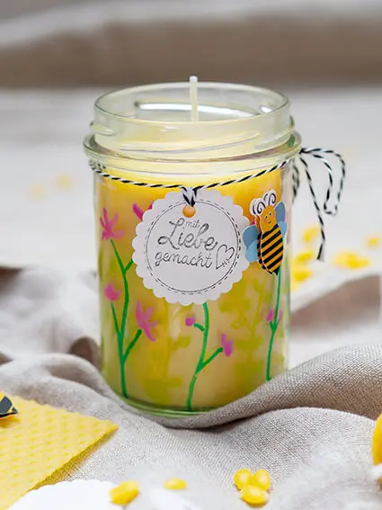 Ein kleines Marmeladenglas, in welches mit Bienenwachs von KNORR prandell eine Kerze gegossen wurde, steht auf einem naturfarbenen Leinentuch. Foto: Johanna Rundel