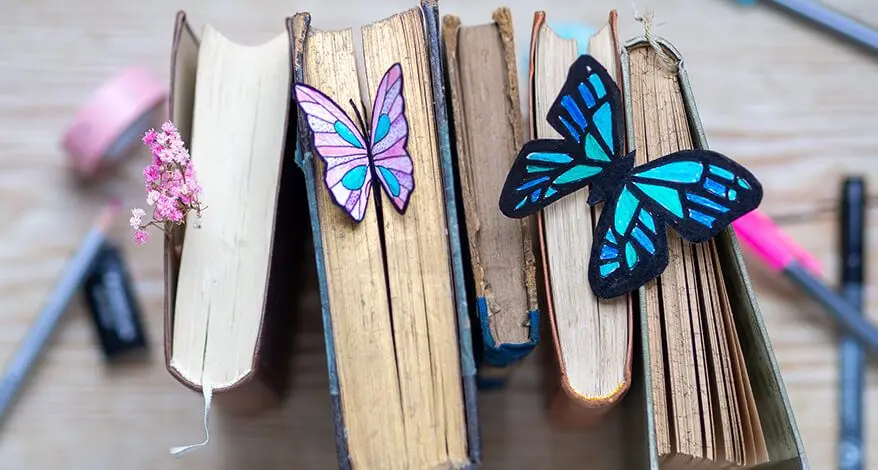 Eine Reihe hochkant gestellter, alter Bücher. Im Buchschnitt stecken zwei Lesezeichen in Schmetterlingsform. Foto: Johanna Rundel 