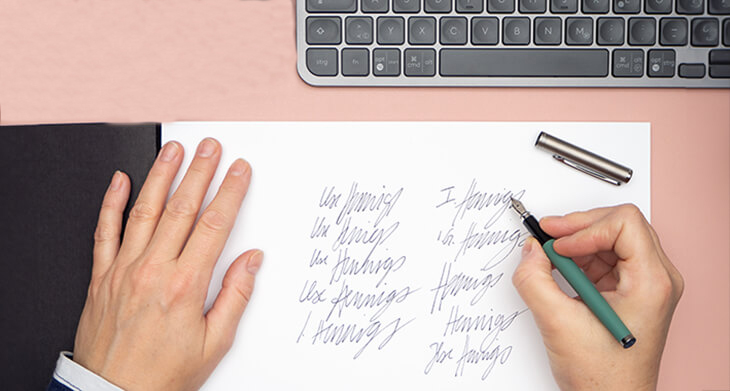 Jemand übt am Schreibtisch auf einem Blatt Papier seine Unterschrift mit einem grünen Füller. Foto: Johanna Rundel