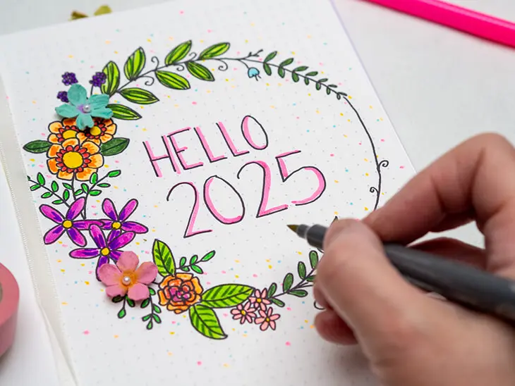 Jemand malt mit einem Goldstift einen Blumenkranz als Deckblatt-Motiv in einem Bullet Journal von Rössler aus. Foto: Johanna Rundel