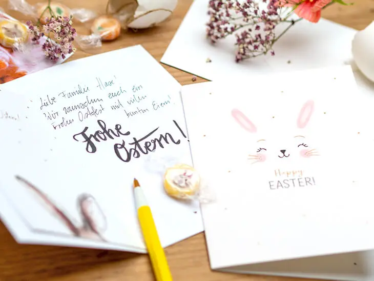 Closeup auf einen Tisch, auf dem verschiedene Osterkarten von Grafik Werkstatt liegen, die gerade geschrieben werden. Foto: Johanna Rundel