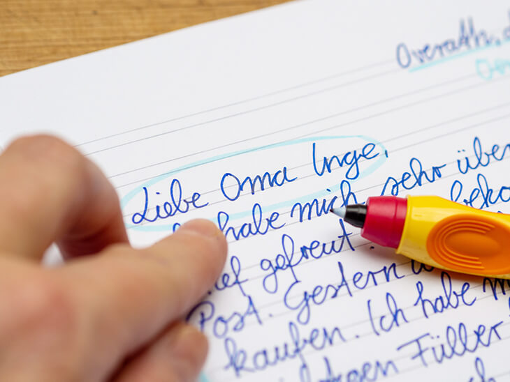 Jemand zeigt mit dem Finger auf ein, mit blauer Farbe eingekreisten, Teil eines persönlichen Briefes. Daneben liegt ein Schreiblern-Tintenroller von Pelikan. Foto: Johanna Rundel