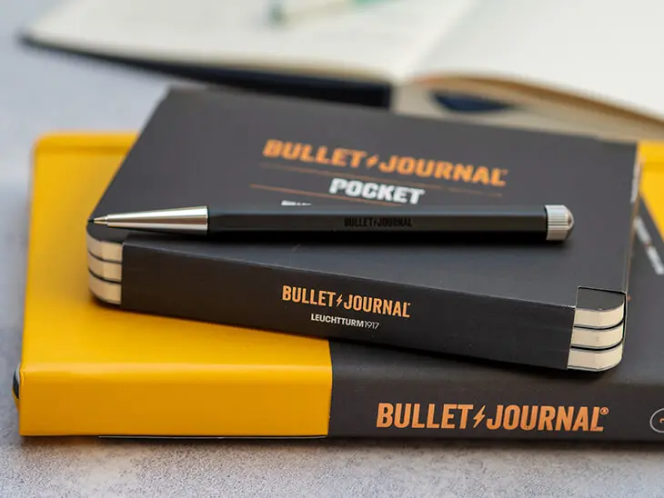Ein schwarzer Drehgriffel liegt auf einer Packung Pocket Journals, das auf einem gelben original Bullet Journal von LEUCHTTURM1917 liegt. Foto: Johanna Rundell