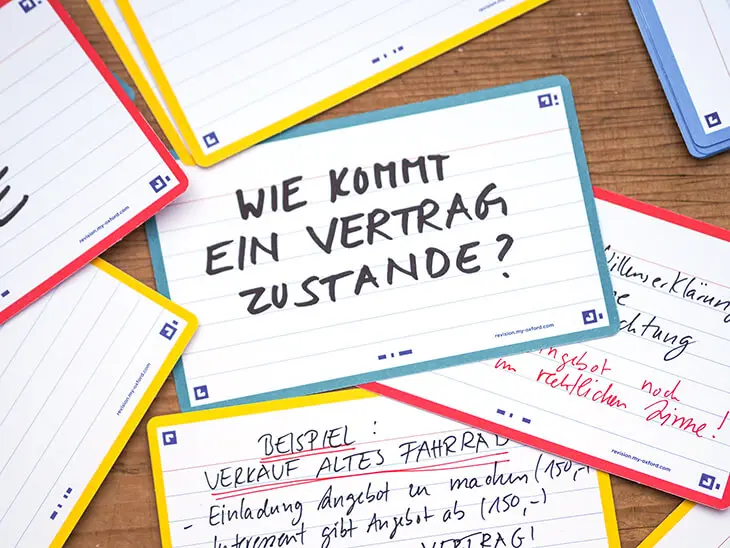 Verschiedene Karteikarten von Oxford mit unterschiedlich farbigen Rändern liegen auf einer Holzoberfläche verteilt. Auf der mittleren Karte steht „Wie kommt ein Vertrag zustande?“. Foto: Johanna Rundel