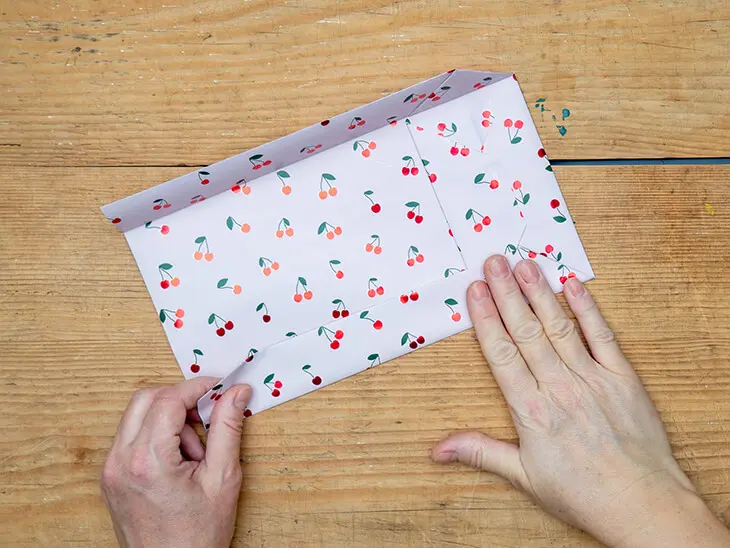 Jemand faltet eine Geschenktüte aus einem Geschenkpapier von STEWO. Foto: Johanna Rundel