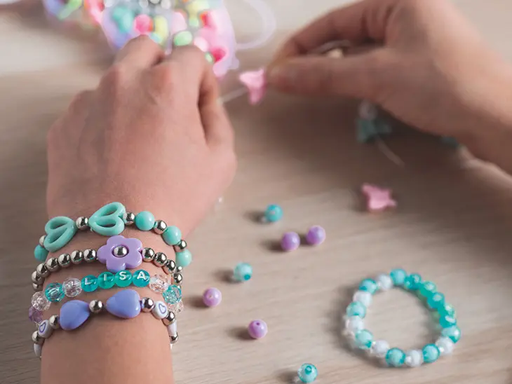 Nahaufnahme eines Kinderarmes mit vier selbstgebastelten Schmuckarmbändern von KNORR prandell