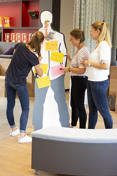 Drei Frauen erarbeiten eine Persona auf einer Pappfigur im Rahmen eines Workshops.