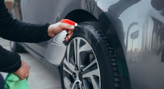 Person reinigt die Felgen eines Autos.