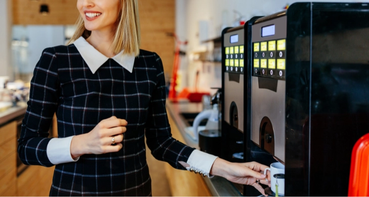 Frau zapft Kaffee am Vollautomaten in moderner Büroküche
