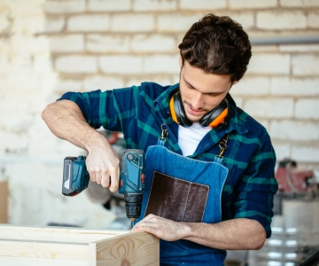 ein Mann bohrt in ein Brett.