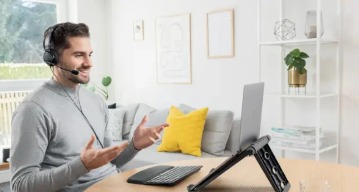 Mann im Homeoffice mit ergonomischem Laptopständer und externer Tastatur