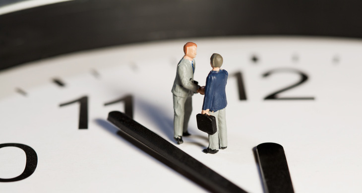 Nahaufnahme einer analogen Uhr mit zwei Miniaturmännchen.