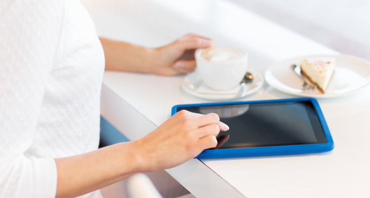 Eine Frau bedient ein Tablet, das auf einem weißen Tisch steht.