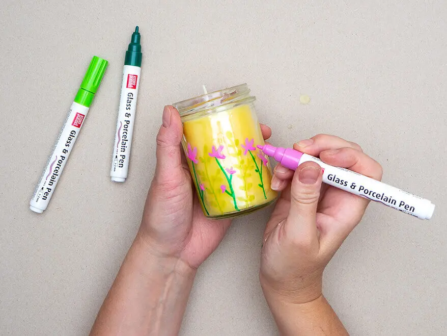 Jemand malt mit Glas- und Porzellanmarkern von KNORR prandell Blumen auf die Außenwand eines Marmeladenglas. Foto: Johanna Rundel
