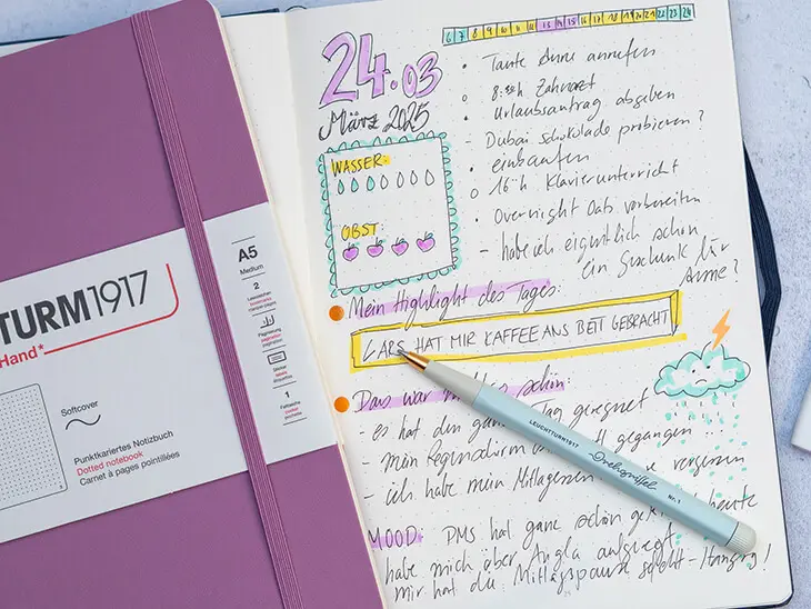 Neben einem aufgeschlagenen Bullet Journal mit einem tagebuchartigen daily log liegt ein lilafarbiges Notizbuch von LEUCHTTURM1917. Foto: Johanna Rundel